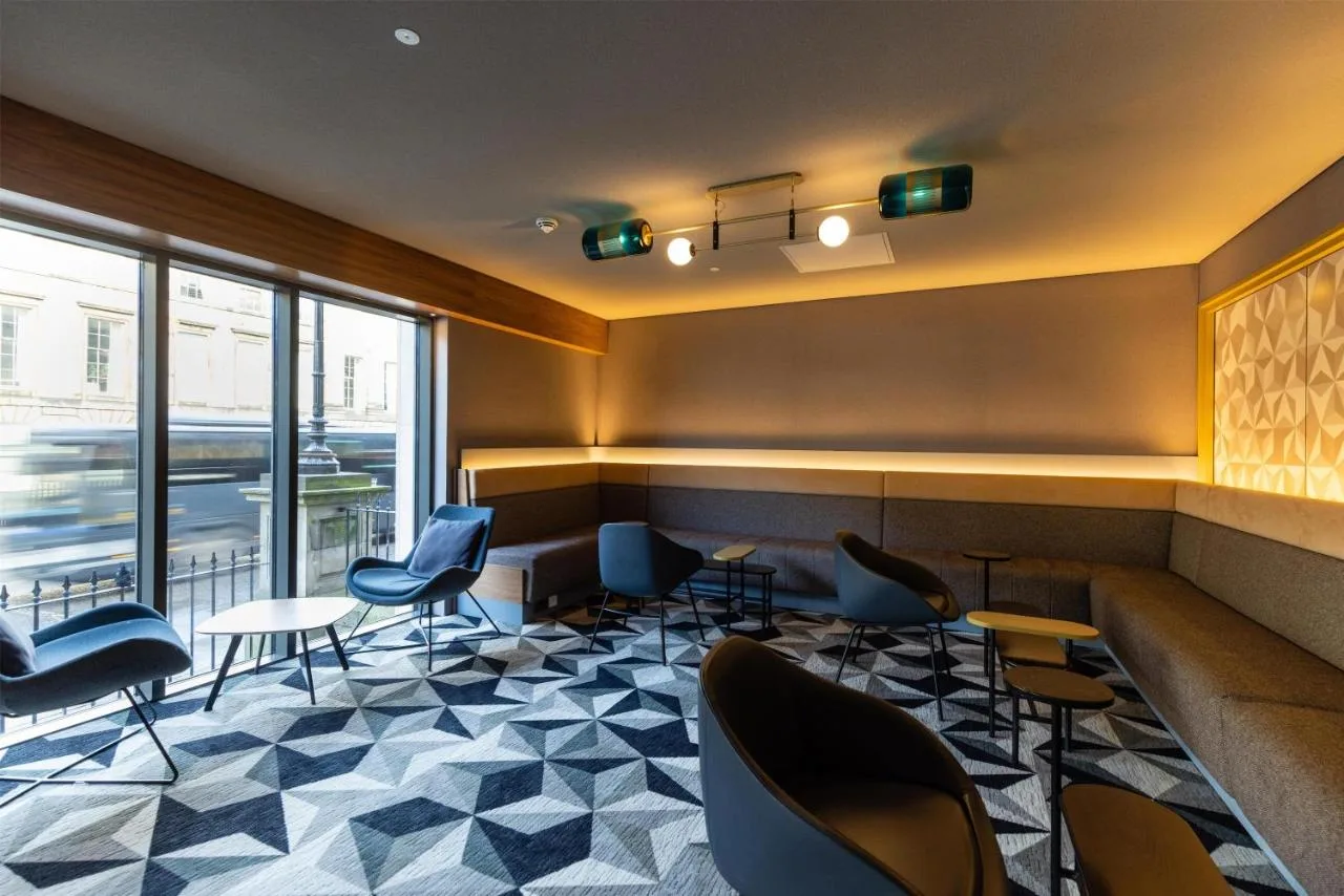 a waiting room with chairs and tables in a building at Yotel Edinburgh in Edinburgh